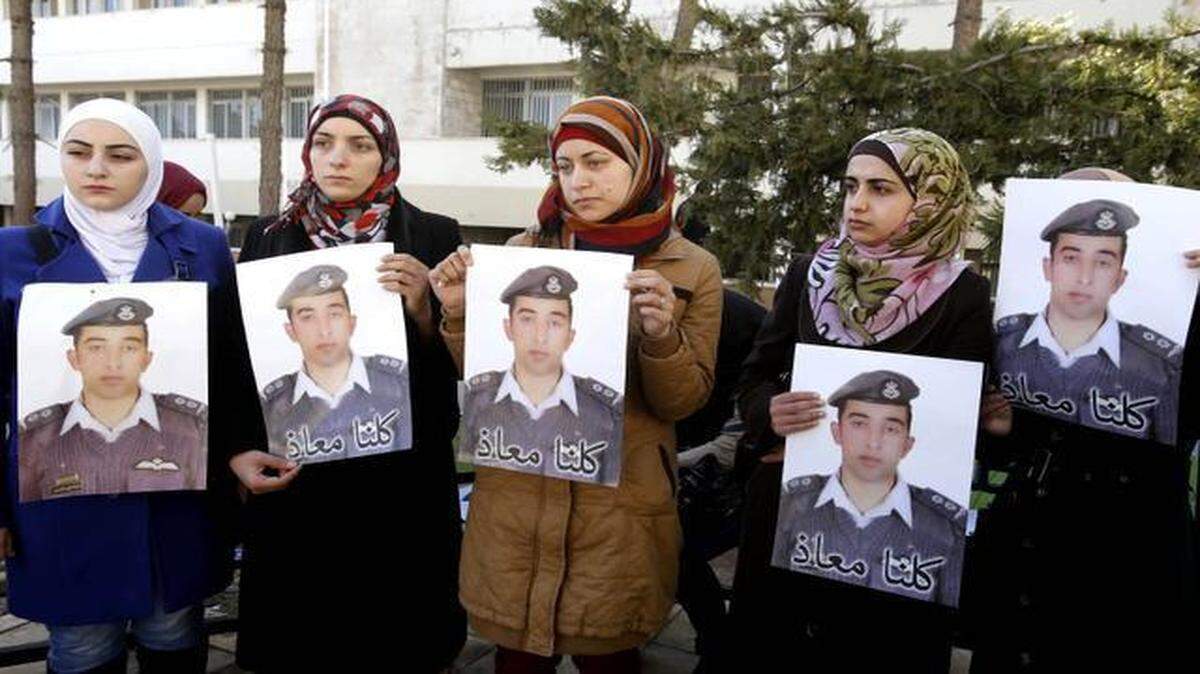 
Anwar al-Tarawneh (center), the wife of Jordanian pilot Lt. Muath al-Kaseasbeh, held a poster of him with Arabic that read, “We are all Muath,” during a protest in Amman, Jordan, shortly before ISIS militants reportedly burned the captured pilot to death.
