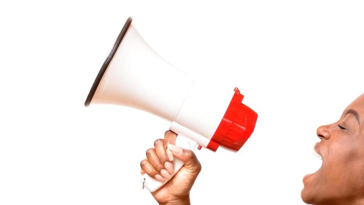 Angry young African woman yelling into a megaphone as she makes her grievances known at a demonstration or rally side view on white