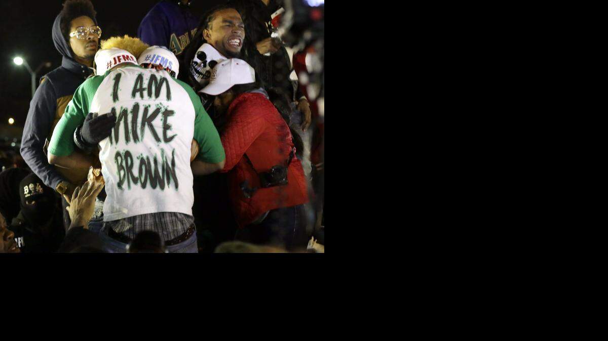 Lesley McSpadden, the mother of Michael Brown, hugs an unidentified man, wearing an I am Mike Brown shirt, after the grand jury decision in Ferguson.