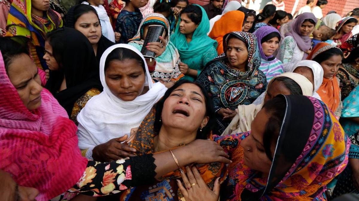 People tried to comfort a Pakistani Christian mother during the funeral of her two daughters, who were killed in a suicide bombing last Sunday.