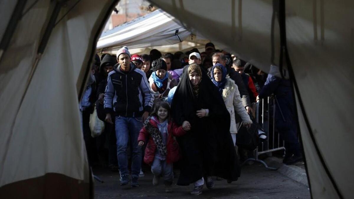 Migrants walk into a tent to register with the police at a refugee center in the southern Serbian town of Presevo. Kansas Gov. Sam Brownback and others have declared they won’t accept Syrian refugees in their states.