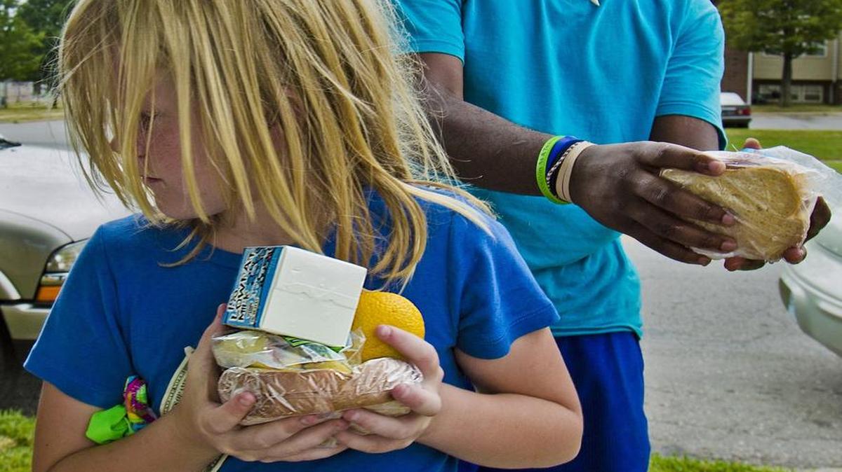 
Courtney Erskin held her food as volunteer Jesse Coleman handed out free lunches as part of a Harvesters Kids Cafe at Grove Park Pool in Kansas City.

