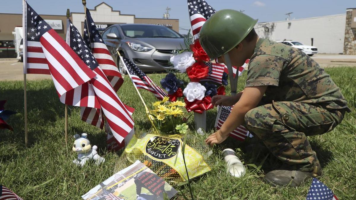 
Eli Arnold, 5, on Friday placed a small flag at a makeshift memorial in front of the Armed Forces Career Center in Chattanooga, Tenn.
