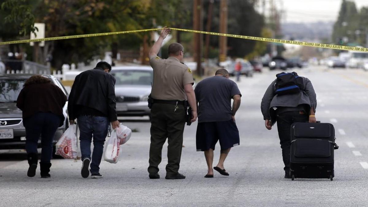 Residents are escorted to their homes near a black SUV that was involved in Wednesday’s police shootout with suspects in a mass shooting in San Bernardino, Calif. The horrific event has prompted new debates about how the nation should react.
