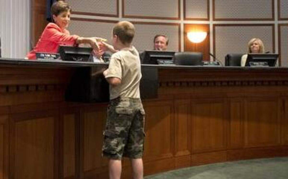 
Spencer Collins, 9, got a handshake and a book from Leawood mayor Peggy Dunn after the Leawood City Council unanimously approved a temporary moratorium on Monday. It exempts the little lending libraries from a city ordinance that prohibits structures in front yards.
