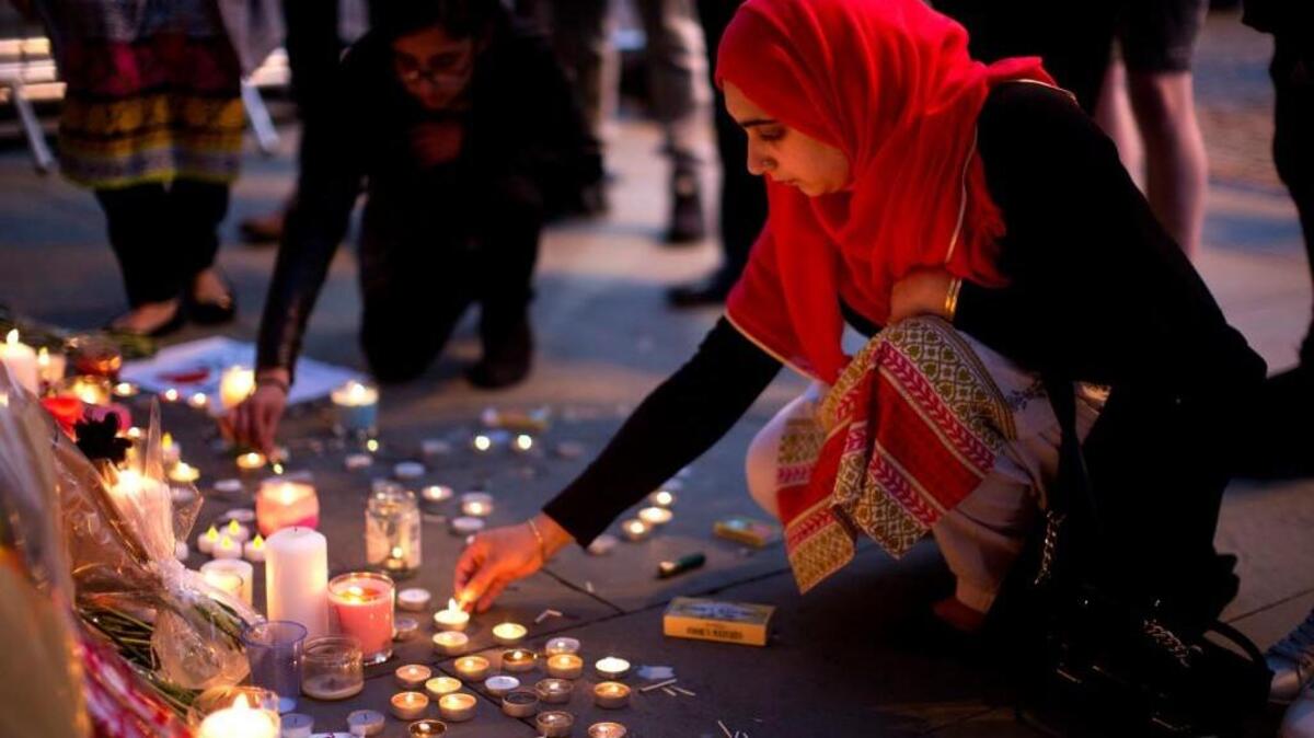 A woman lights candles after a vigil in Albert Square, Manchester, England, Tuesday May 23, 2017, the day after the suicide attack at an Ariana Grande concert that left 22 people dead.
