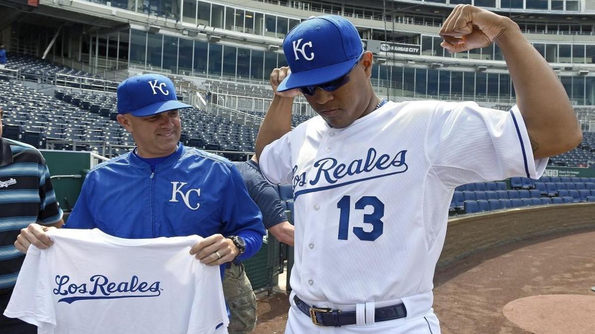Kansas City Royals catcher Salvador Perez modeled the Los Reales game jersey that the team wore last summer. At left, catching coach Pedro Grifol held a T-shirt with Los Reales written across it that was given out as part of a T-shirt Tuesday promotion. And this year, Latino fans will be able to listen in on 40 Royals home games in Spanish on KYYS (1250 AM).