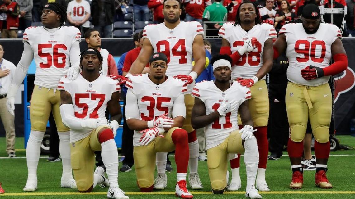 San Francisco 49ers' Eli Harold (57), Eric Reid (35) and Marquise Goodwin (11) kneel during the national anthem before an NFL football game against the Houston Texans.