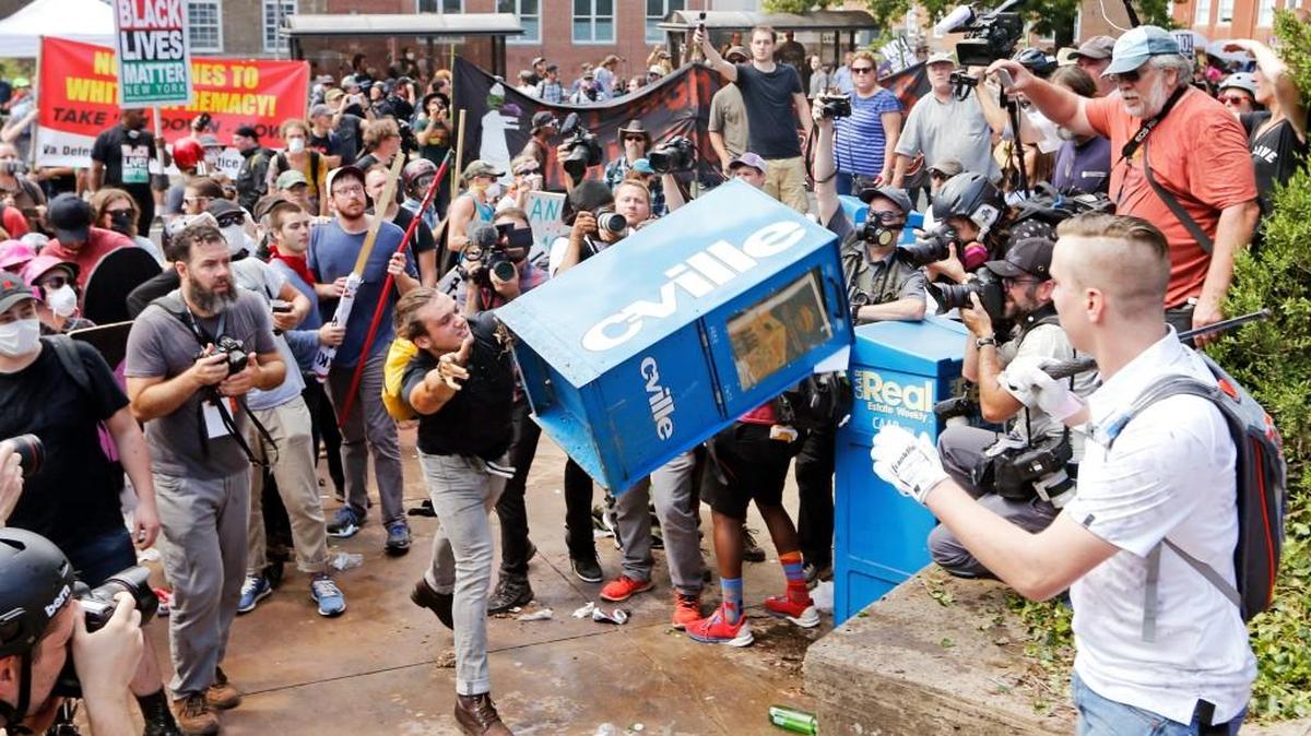 In this Aug. 12, 2017 file photo, white nationalist demonstrators, right, clash with a counter-demonstrator as he throws a newspaper box at the entrance to Lee Park in Charlottesville, Va.