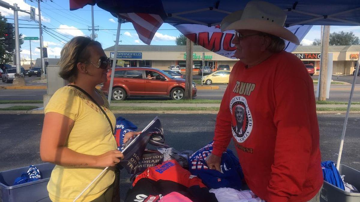 Stephanie Waldron, who works for a nonprofit, buys her second Trump flag and third T-shirt from Virginia vendor Whitey Taylor in Springfield, Mo.