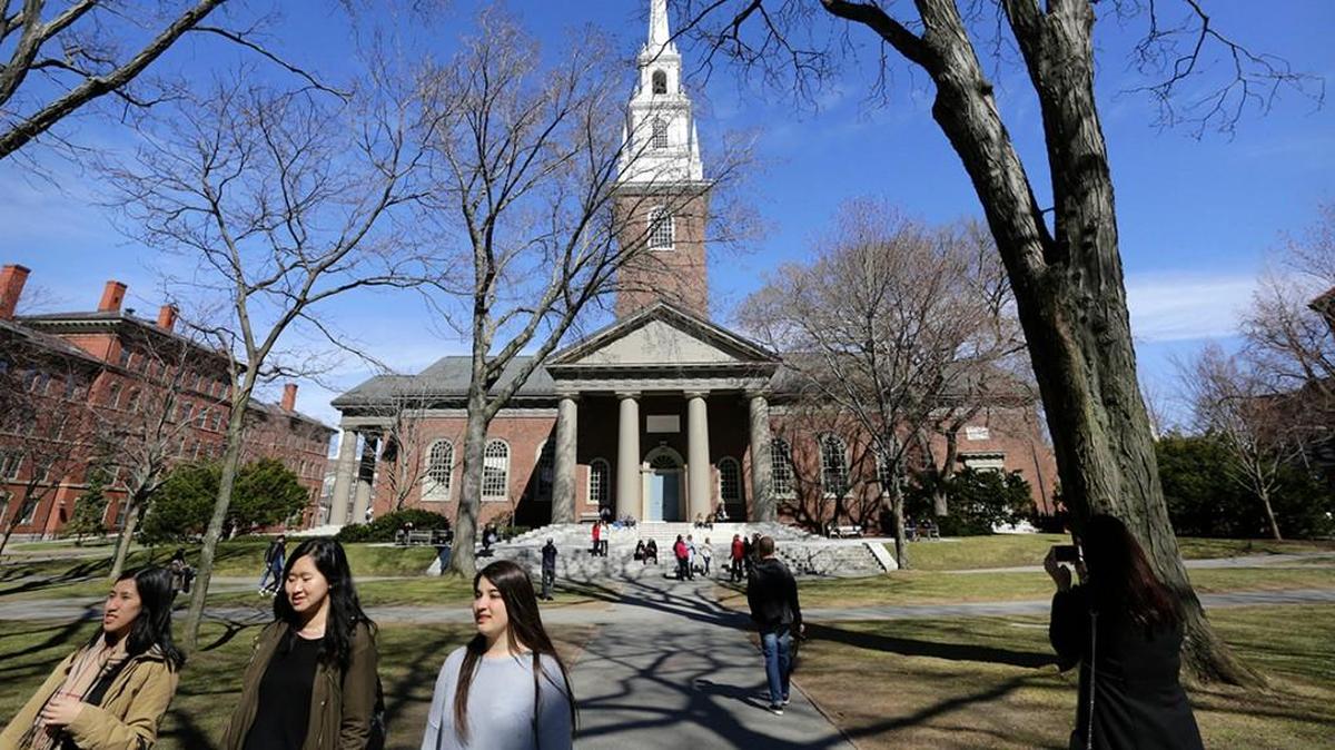FILE - In this March 13, 2016, file photo, people walk near Memorial Church on the campus of Harvard University in Cambridge, Mass. The university’s first female president, Drew Faust, announced Friday, May 6, 2016, that students who join Harvard’s male-only social clubs won’t be able to serve as sports captains or leaders of other campus groups starting in fall 2017. (AP Photo/Steven Senne, File)