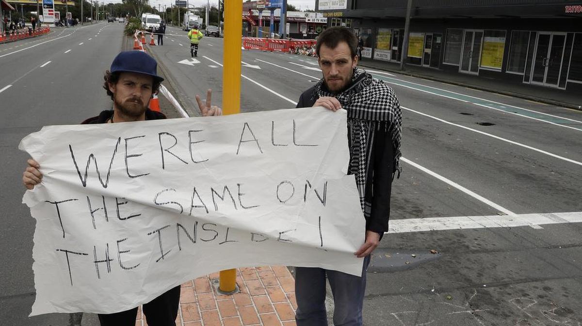 Linwood mosque shooting survivor Elliot Dawson, right, and a friend Shay Kenny hold a sign at a intersection near the mosque in Christchurch, New Zealand, Sunday, March 17, 2019. The live-streamed attack by an immigrant-hating white nationalist killed dozens of people as they gathered for weekly prayers in the Friday before.