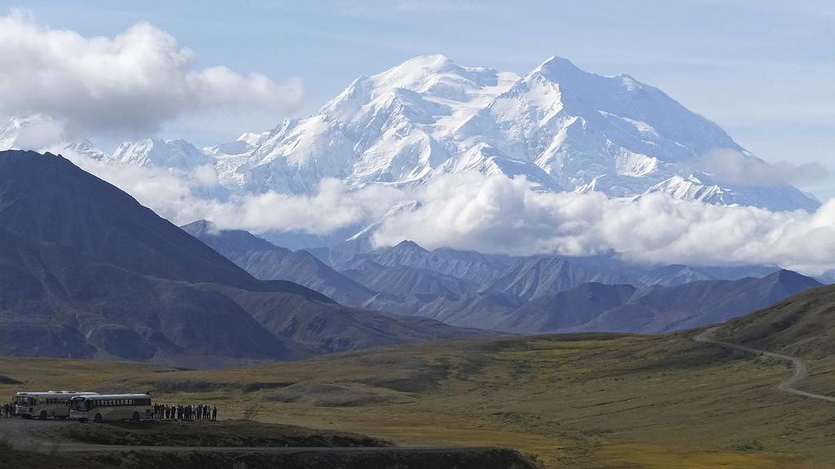 Sightseeing buses and tourists at a pullout popular for taking in views of North America’s tallest peak, Denali, in Denali National Park and Preserve, Alaska.