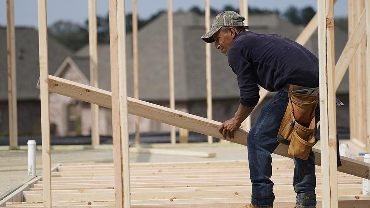 High demand is stoking inflation in building materials like lumber, which is up more than fourfold from a year ago. A carpenter aligns a beam for a wall frame at a new house site.