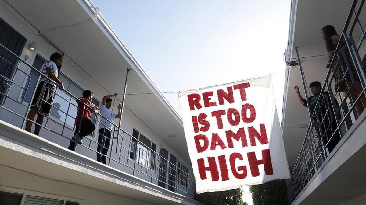 Organizers with Housing Long Beach, a local advocacy group pushing for rent control and eviction protections, hangs up a sign in the courtyard of the apartment complex on Cedar Avenue, during a movie night they helped put on with tenants.