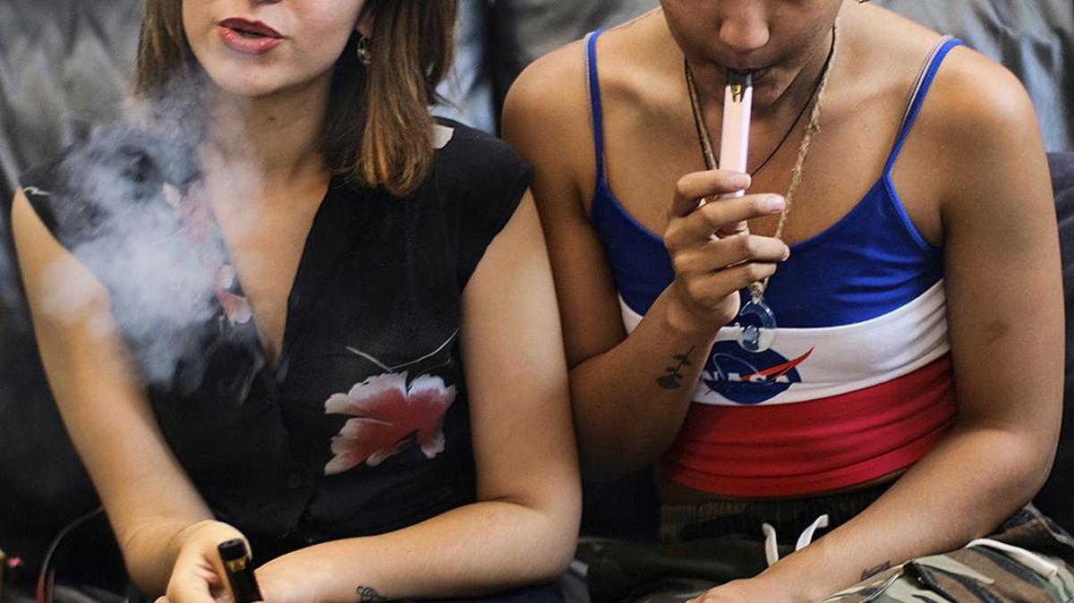 In this June 8, 2019, photo, two women smoke cannabis vape pens at a party in Los Angeles. Marijuana use among college students has risen to the highest levels since the 1980s.