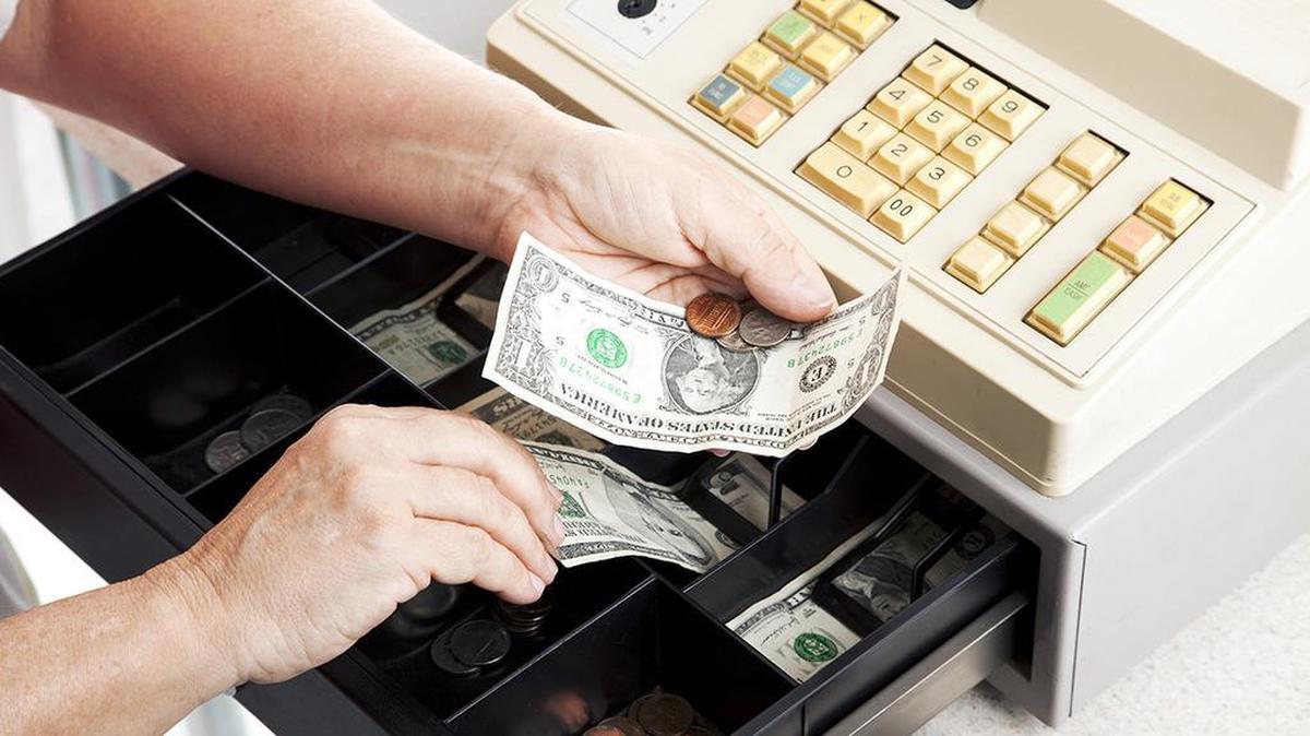 Horizontal view of an open cash register drawer as a cashier makes change.