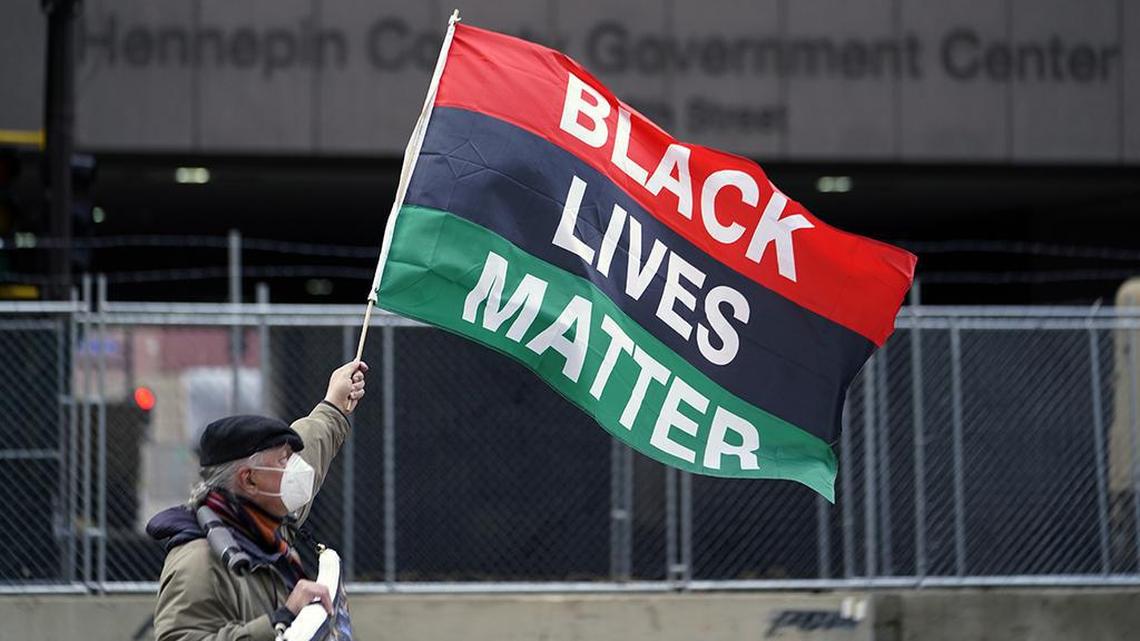 A protesters waves a Black Lives Matter flag across the street from the Hennepin County Government Center, Wednesday, April 7, 2021, in Minneapolis where testimony continues in the trial of former Minneapolis police officer Derek Chauvin continues. Chauvin is charged with murder in the death of George Floyd during an arrest last May in Minneapolis. (AP Photo/Jim Mone)