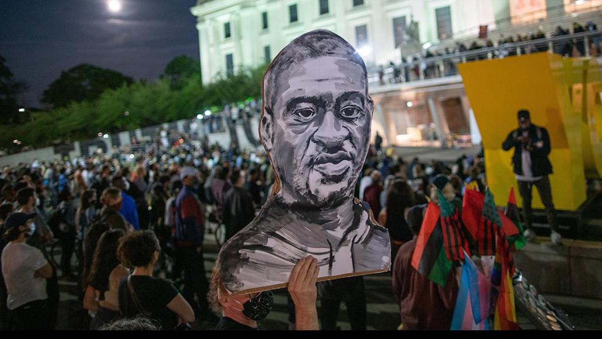 A man holds up a poster of George Floyd as demonstrators attend a vigil at Brooklyn Museum to remember the murder of Floyd, late Tuesday, May 25, 2021, in New York. (AP Photo/Eduardo Munoz Alvarez)