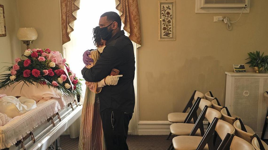 In this May 2, 2020, file photo, siblings Erika and Dwayne Bermudez comfort one another during a short viewing of their mother, Eudiana Smith, who died of coronavirus, at The Family Funeral Home in Newark, New Jersey.