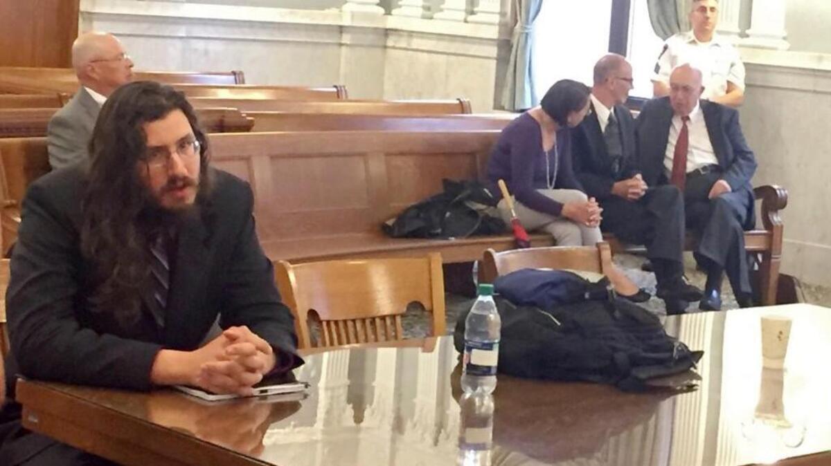 Michael Rotondo, left, sits during an eviction proceeding in Syracuse, N.Y., brought by his parents, Mark and Christina, of Camillus. The two parents confer with their lawyer, Anthony Adorante, in the court gallery behind. Rotondo told the judge Tuesday, May 22, 2018, he knows his parents want him out of their home. (Douglass Dowty /The Syracuse Newspapers via AP)