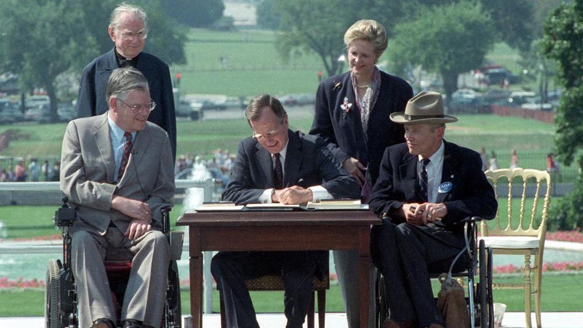 In this July 26, 1990 file photo, President George H. W. Bush signs the Americans with Disabilities Act during a ceremony on the South Lawn of the White House. Joining the president are, from left, Evan Kemp, chairman of the Equal Opportunity Employment Commission; Rev. Harold Wilke; Sandra Parrino, chairman of the National Council on Disability, and Justin Dart, chairman of The President’s Council on Disabilities.