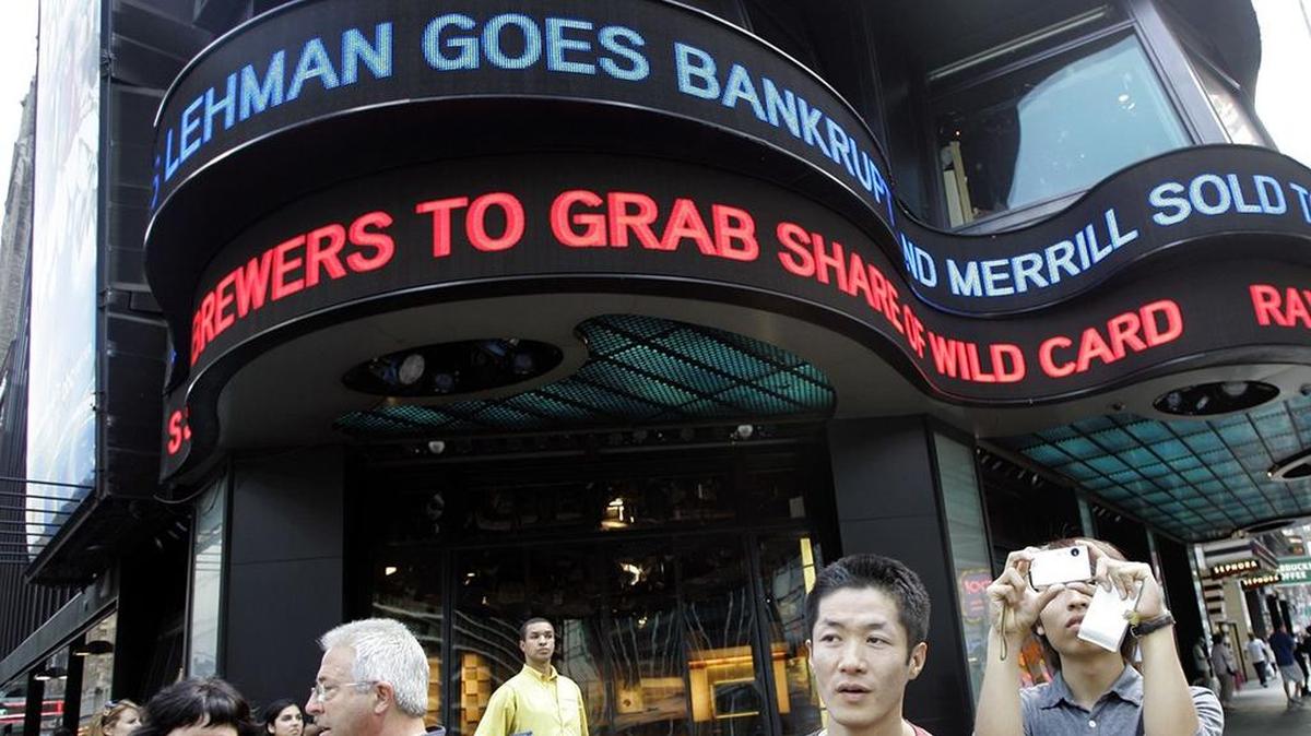 In this Sept. 15, 2008, file photo tourists take pictures in New York’s Times Square as the days financial news about the bankruptcy of Lehman Brothers is displayed on the ABC news ticker.