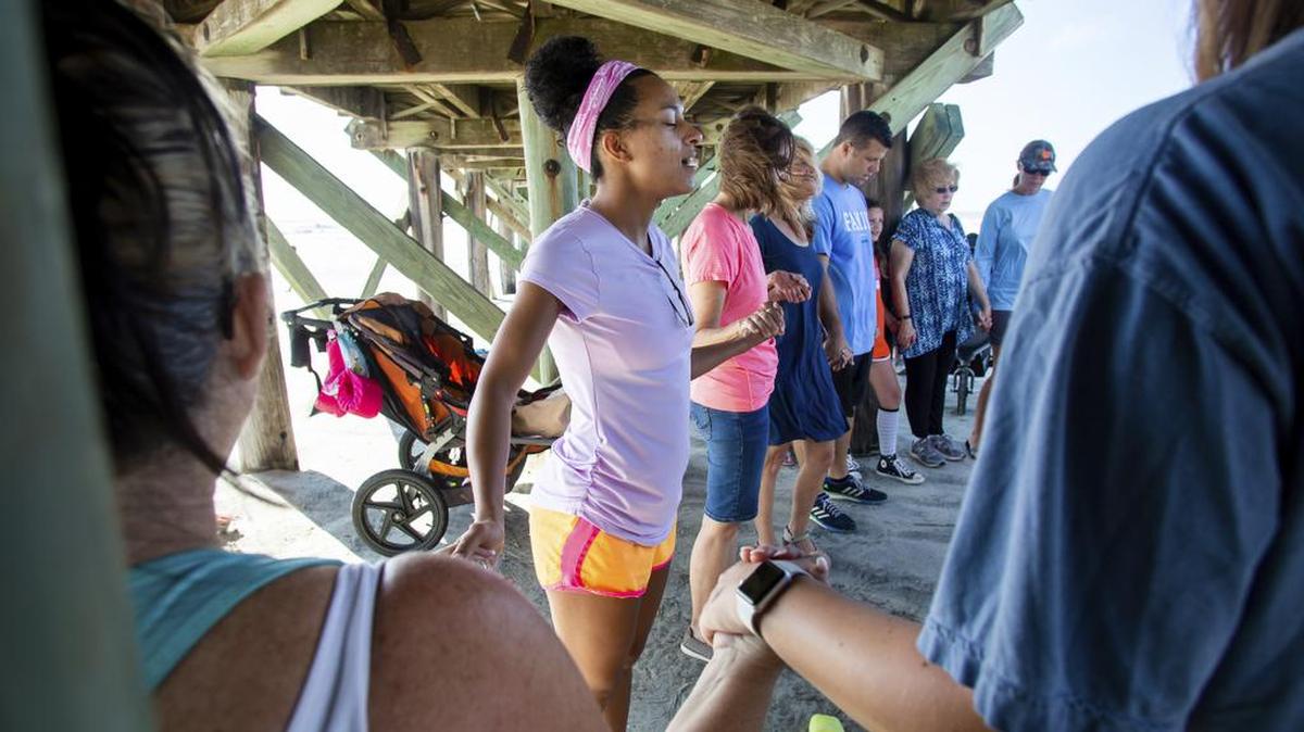 Angelica Annichino, center, holds hands with DeepWater Church members and Isle of Palms, South Carolina, residents in prayer under the Isle of Palms pier as Hurricane Dorian spins out in the Atlantic ocean Tuesday, September 3.
