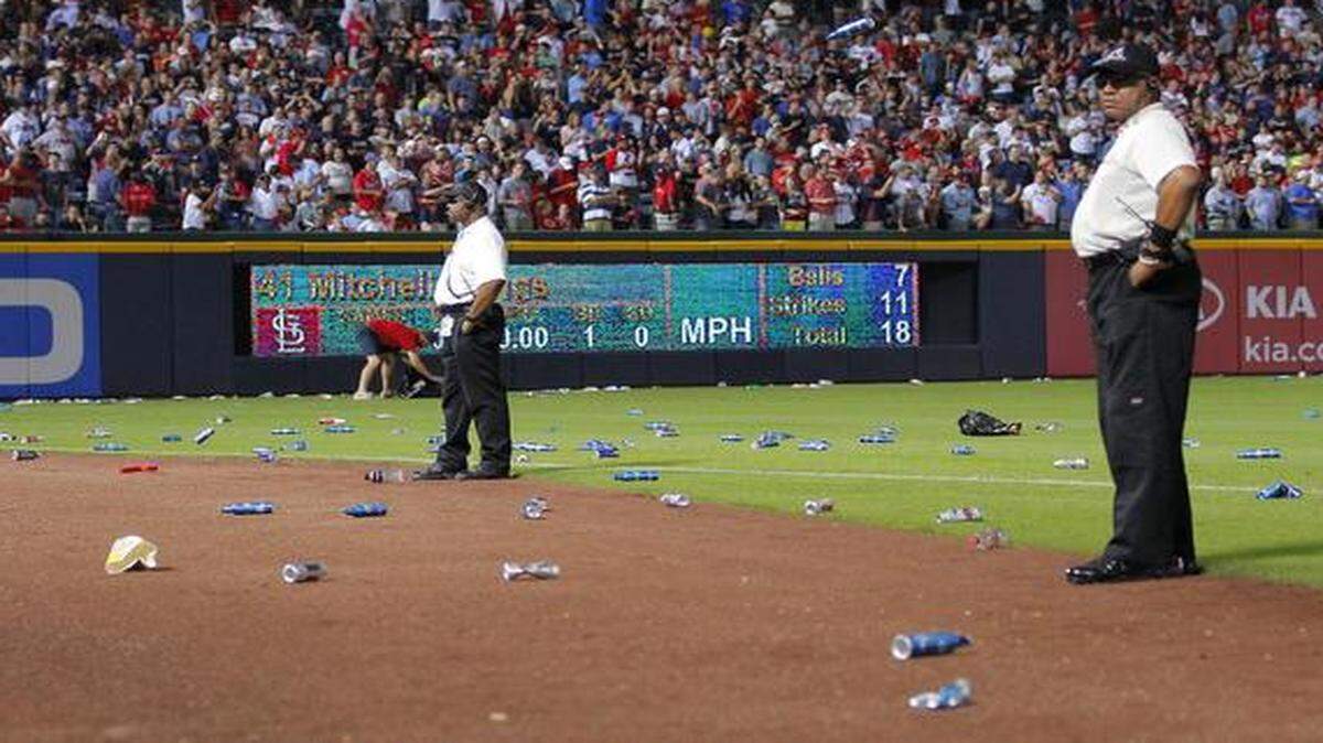 
Atlanta Braves officials picked up trash on the field as security stood by during the eighth inning of the National League Wild Card Game against the St. Louis Cardinals in 2012.
