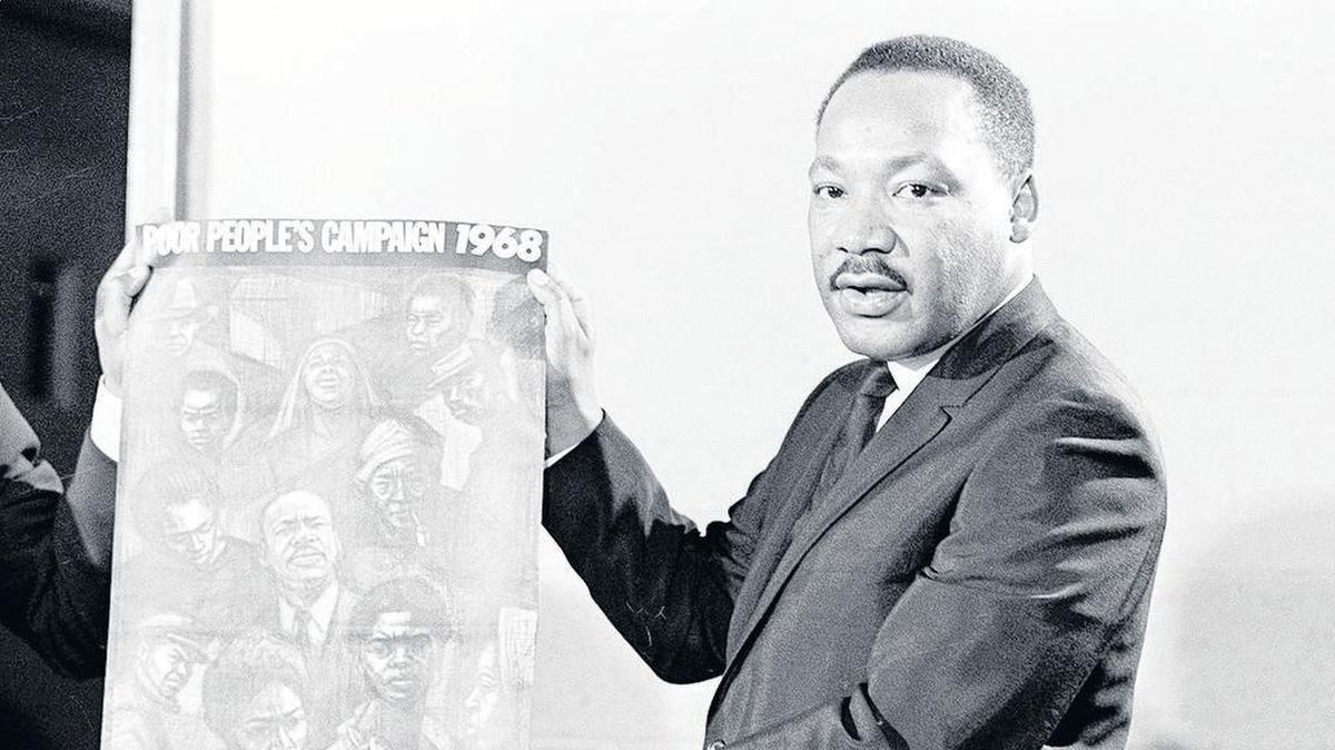 In this March 4, 1968 file photo, civil rights leader the Rev. Martin Luther King, Jr. displays the poster to be used during his Poor People’s Campaign. Thousands of anti-poverty activists have launched a campaign in recent weeks modeled after King’s.