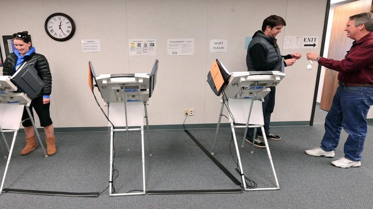 
Election worker David Christmore (right) collects the electronic voting card from Matt Harter as his wife Kathryn Harter finishes voting at the Johnson County Election Office, 2101 E. Kansas City Road, in Olathe.
