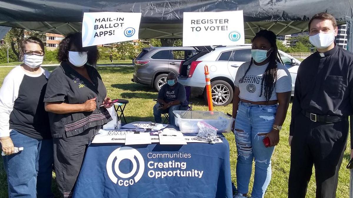 Danise Hartsfield, Communities Creating Opportunity executive director (center-left), stands ready at the voter registration table with (left to right) Karen Rogers, Alexandria Thompson, and Father Taylor Tracy during the March on Kansas City for Justice and Peace on Sept. 4, 2020.