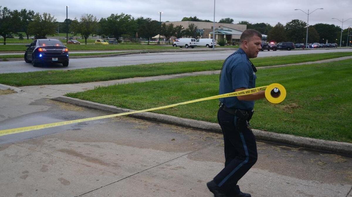 Police officers investigate a shooting that killed two men Aug. 25 outside the Brush Creek Community Center in Kansas City.