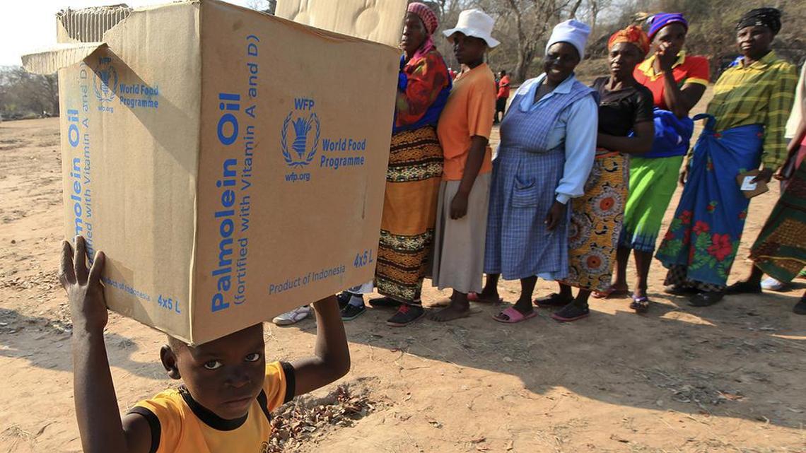 In this Sept. 9, 2015 file photo, a child carries a parcel from the United Nations World Food Program in Mwenezi, Zimbabwe. The program won the 2020 Nobel Peace Prize for its efforts to combat hunger and food insecurity around the globe.