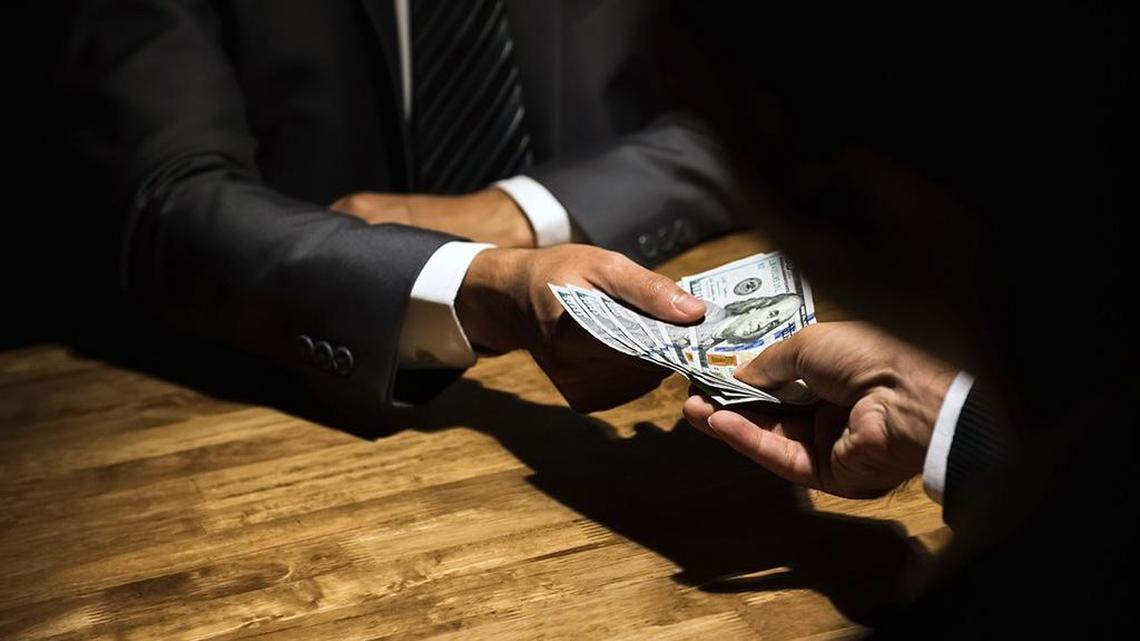 Dishonest businessman secretly giving money to his partner in the dark - bribery scam and venality concepts