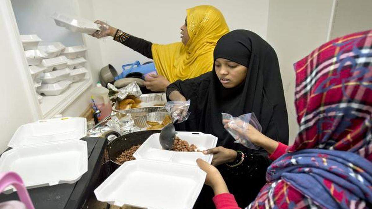 
Asha Sheikh (from top), Gudon Abdi and Kadija Yusuf served food after prayers last month at the Masjidu Nuur Islamic Community Center, 2639 E. 11th St.
