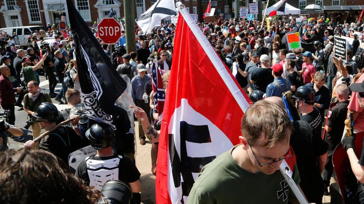 This Saturday, Aug. 12, 2017 image shows a white supremacist carrying a Nazi flag into the entrance to Emancipation Park in Charlottesville, Va.