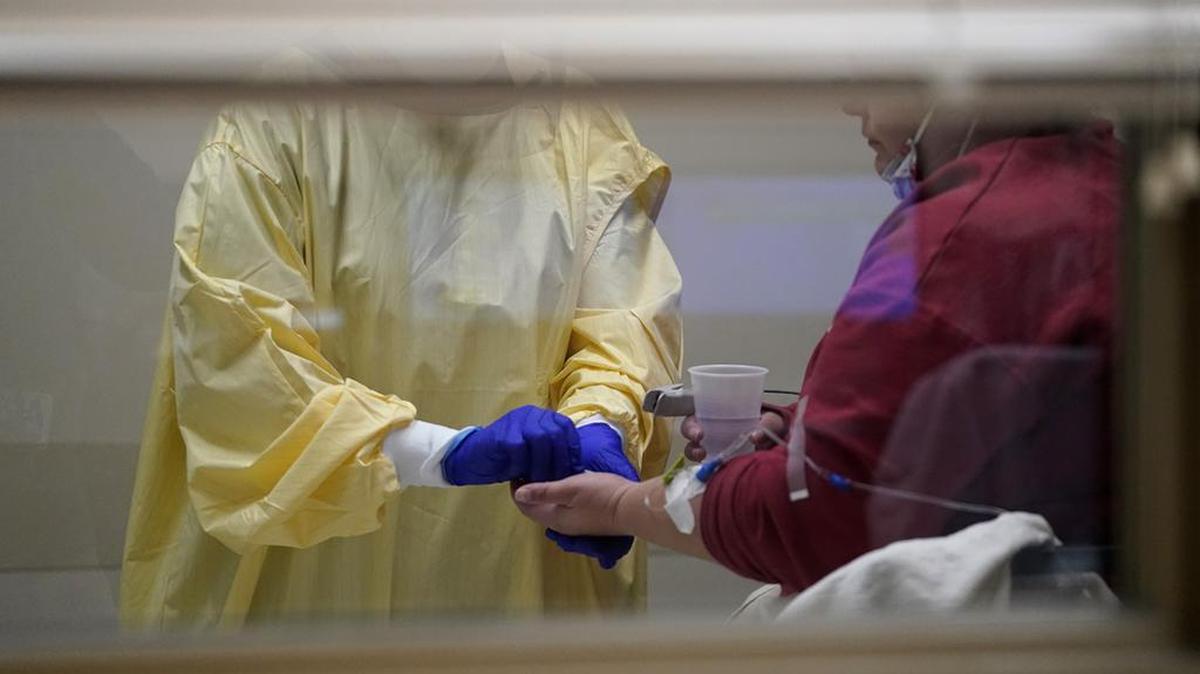 Registered nurse Chrissie Burkhiser, left, hands medication to a COVID-19 patient inside the emergency room at Scotland County Hospital Tuesday, Nov. 24, 2020, in Memphis, Mo. The tiny hospital in rural northeast Missouri is seeing an alarming increase in coronavirus cases. (AP Photo/Jeff Roberson)