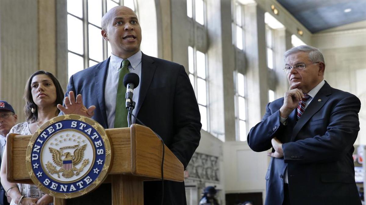
U.S. Sen. Robert Menendez of New Jersey (right) listened as a fellow Democrat, Sen. Cory Booker, answered a question about his Railroad Reform, Enhancement and Efficiency Act at Newark Penn Station. 
