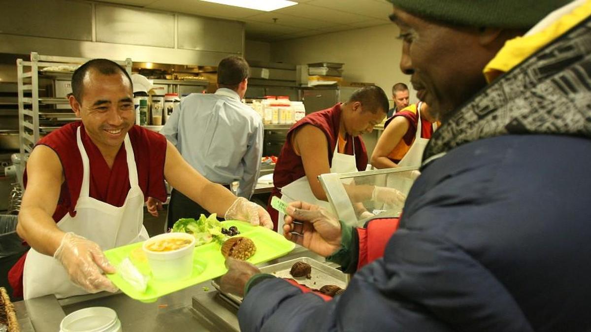 In this April, 2009 photo, Episcopal Community Services welcomed Tibetan Buddhist monks including Sangyal Gyatso, who handed a plate of food to Patricio Welsh at the Kansas City Community Kitchen.