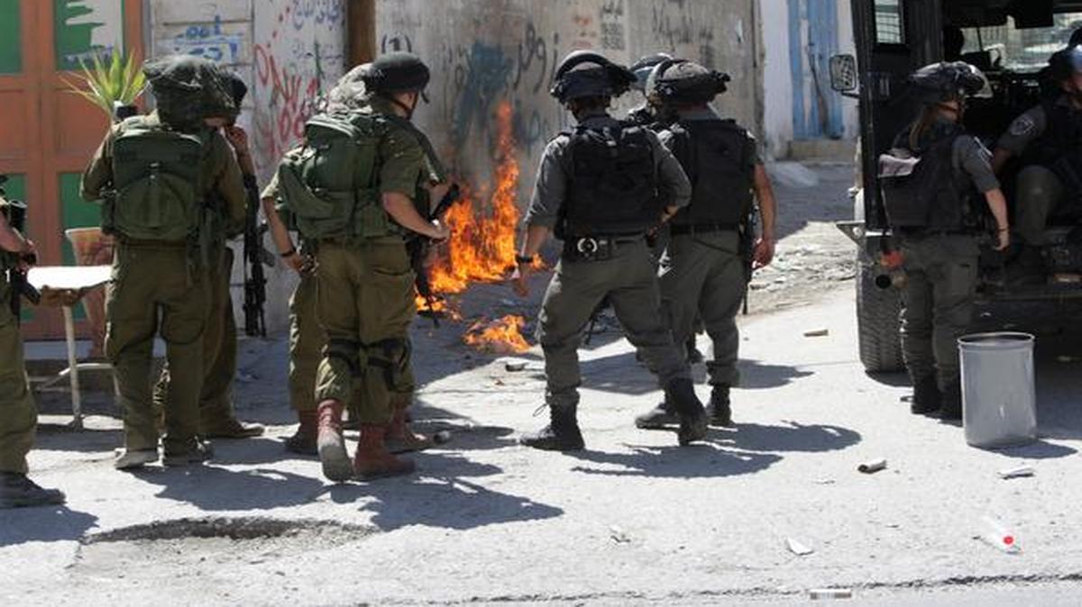 
Israeli soldiers gather by flames created by a Molotov cocktail thrown by Palestinians during clashes in Hawara village near the West Bank city of Nablus.
