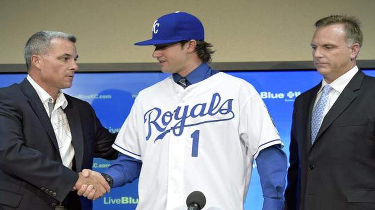 
Royals first-round draft pick, Brandon Finnegan, shook hands with general manager Dayton Moore after putting on a Royals jersey next to Royals director of scouting, Lonnie Goldberg, in June.
