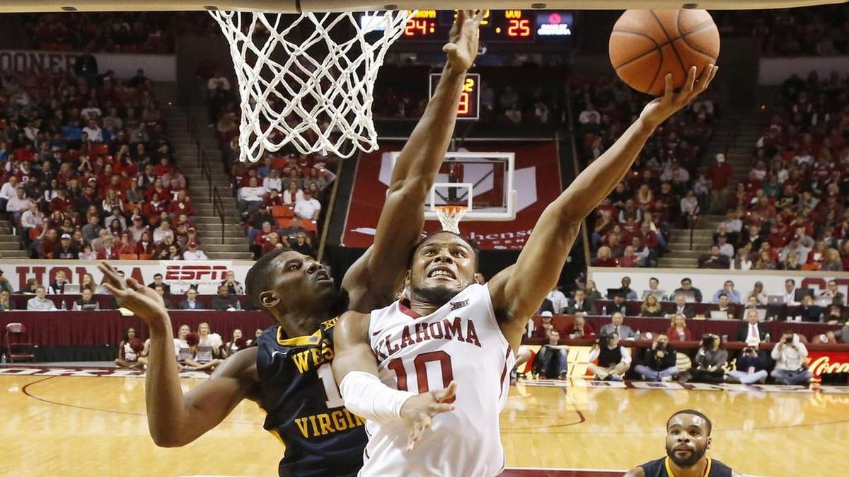 Oklahoma guard Jordan Woodard drove past West Virginia forward Jonathan Holton during a Sooners’ victory Saturday.