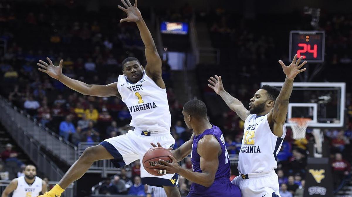 TCU’s Brandon Parrish (center) felt the heat of West Virginia’s full-court press, applied by Johnathan Holton (left) and Tarik Phillip, in their Big 12 Tournament game Thursday at the Sprint Center.