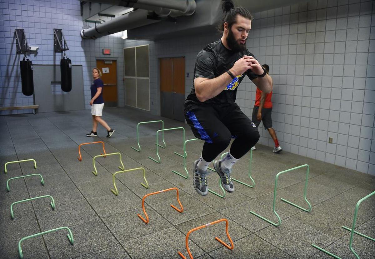 Under the supervision of Andrea Hudy (left rear), Ben Heeney completed a series of jumps that get progressively more difficult. Heeney is training in preparation for a career in the NFL.