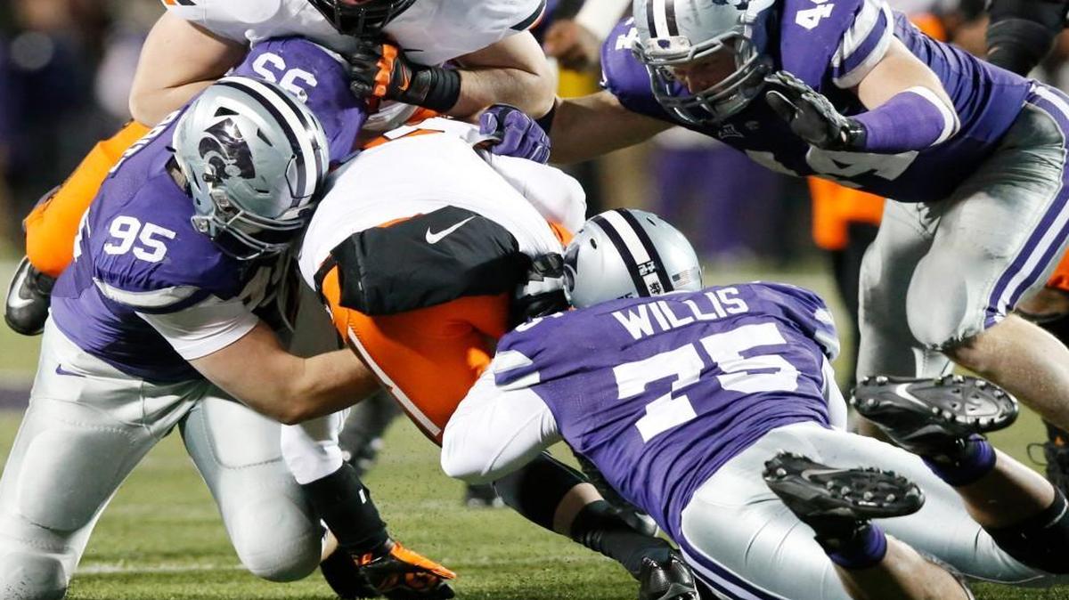 
K-State defenders Jordan Willis, front, Travis Britz, left, and Ryan Mueller bring down Oklahoma State quarterback Daxx Garman last season in Manhattan.
