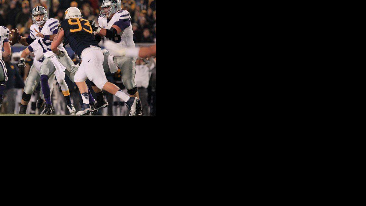 Kansas State quarterback Jake Waters (15) looks for an open receiver as West Virginia's Kyle Rose (93) closes in during Thursday's football game in Morgantown.