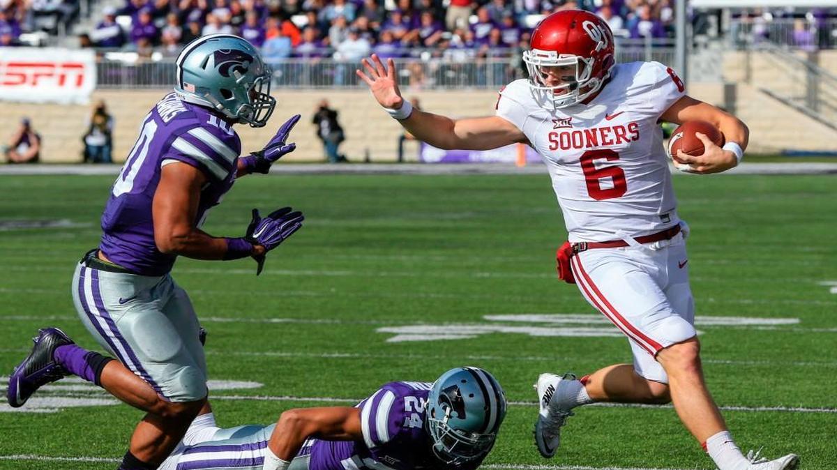 Oklahoma quarterback Baker Mayfield ran away from Kansas State defensive backs Donnie Starks (left) and Nate Jackson.