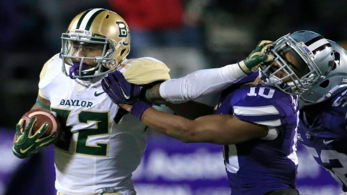 Baylor running back Shock Linwood (32) stiff-arms Kansas State defensive back Donnie Starks (10) during the second half of Thursday’s Big 12 football game in Manhattan.