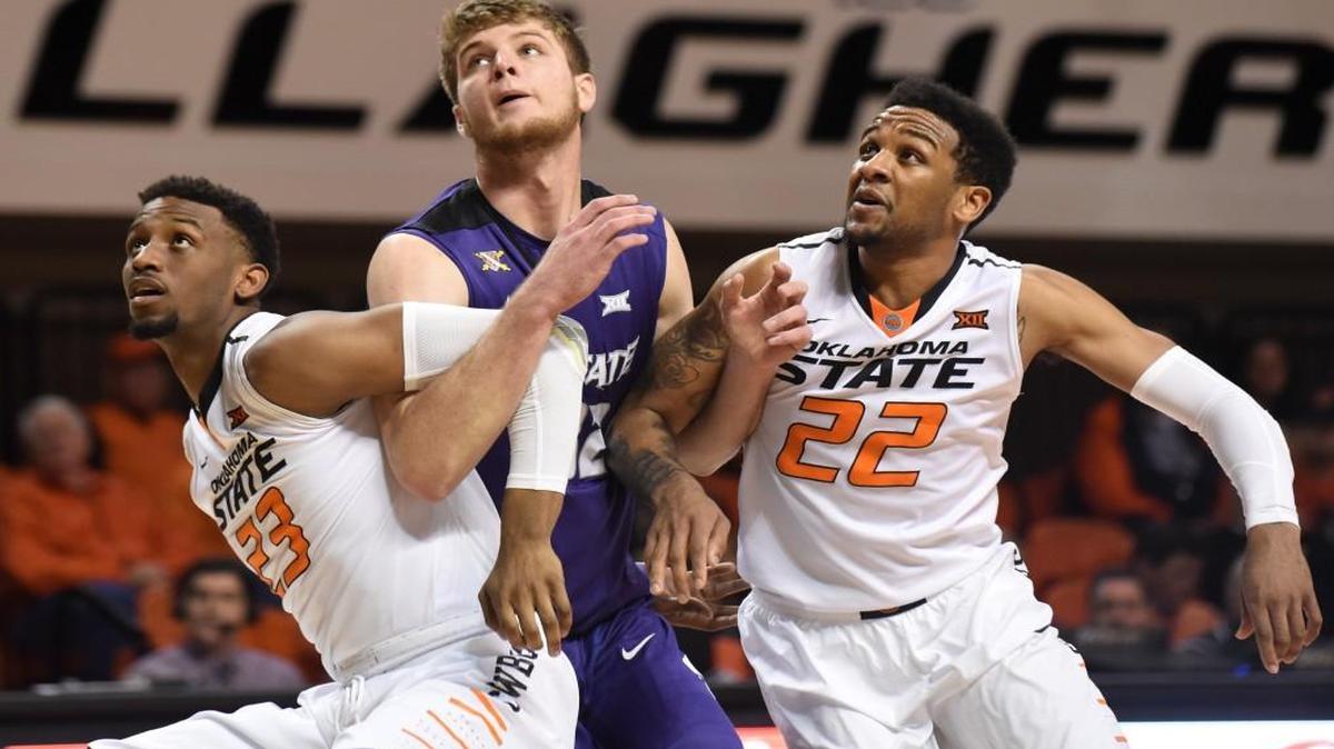 Kansas State forward Dean Wade (center) was blocked out by Oklahoma State forward Leyton Hammonds (left) and guard Jeff Newberry during Saturday’s game.